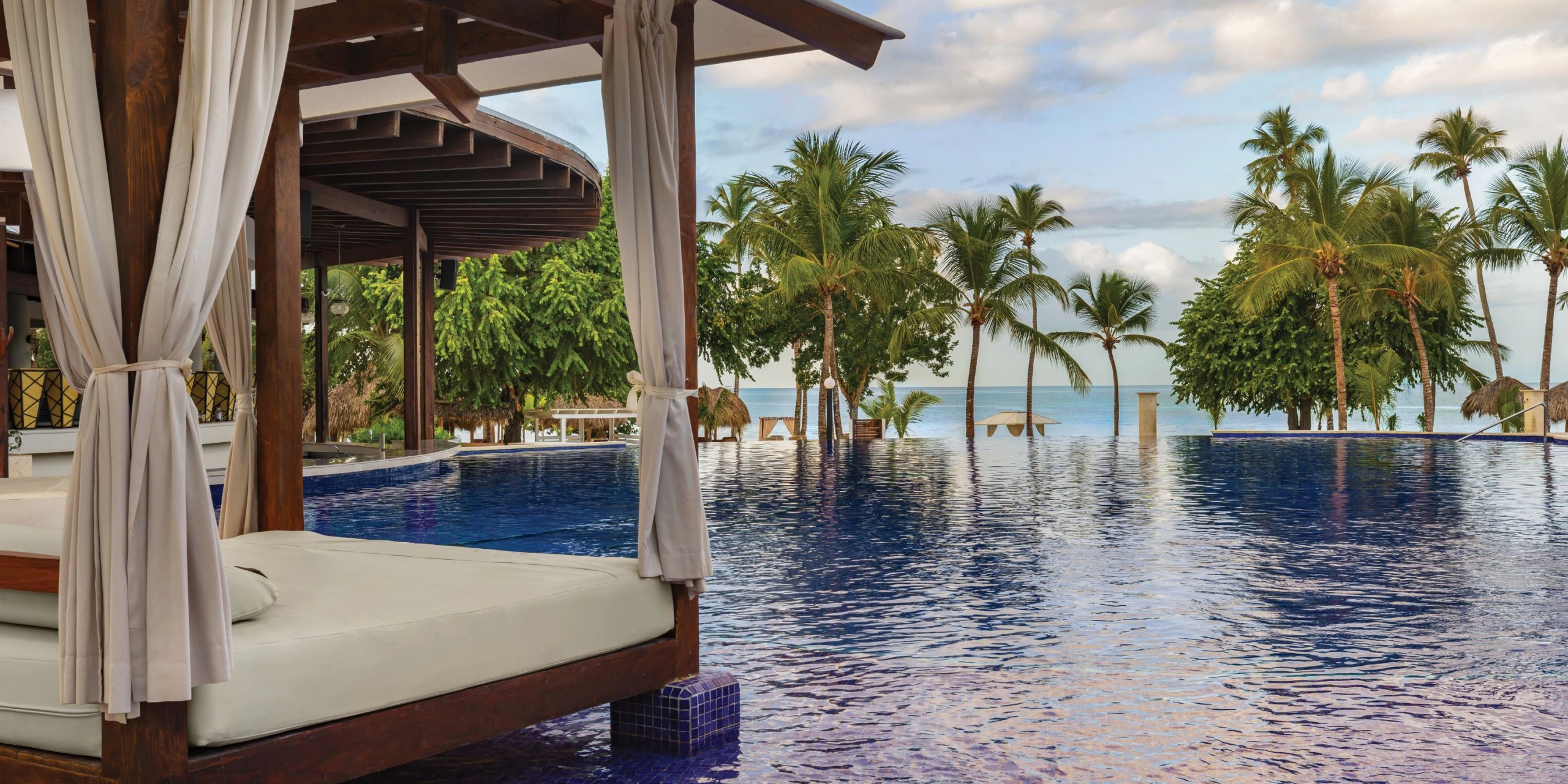 Shaded cabana beside the infinity pool at Secrets La Romana Resort & Spa with ocean views.