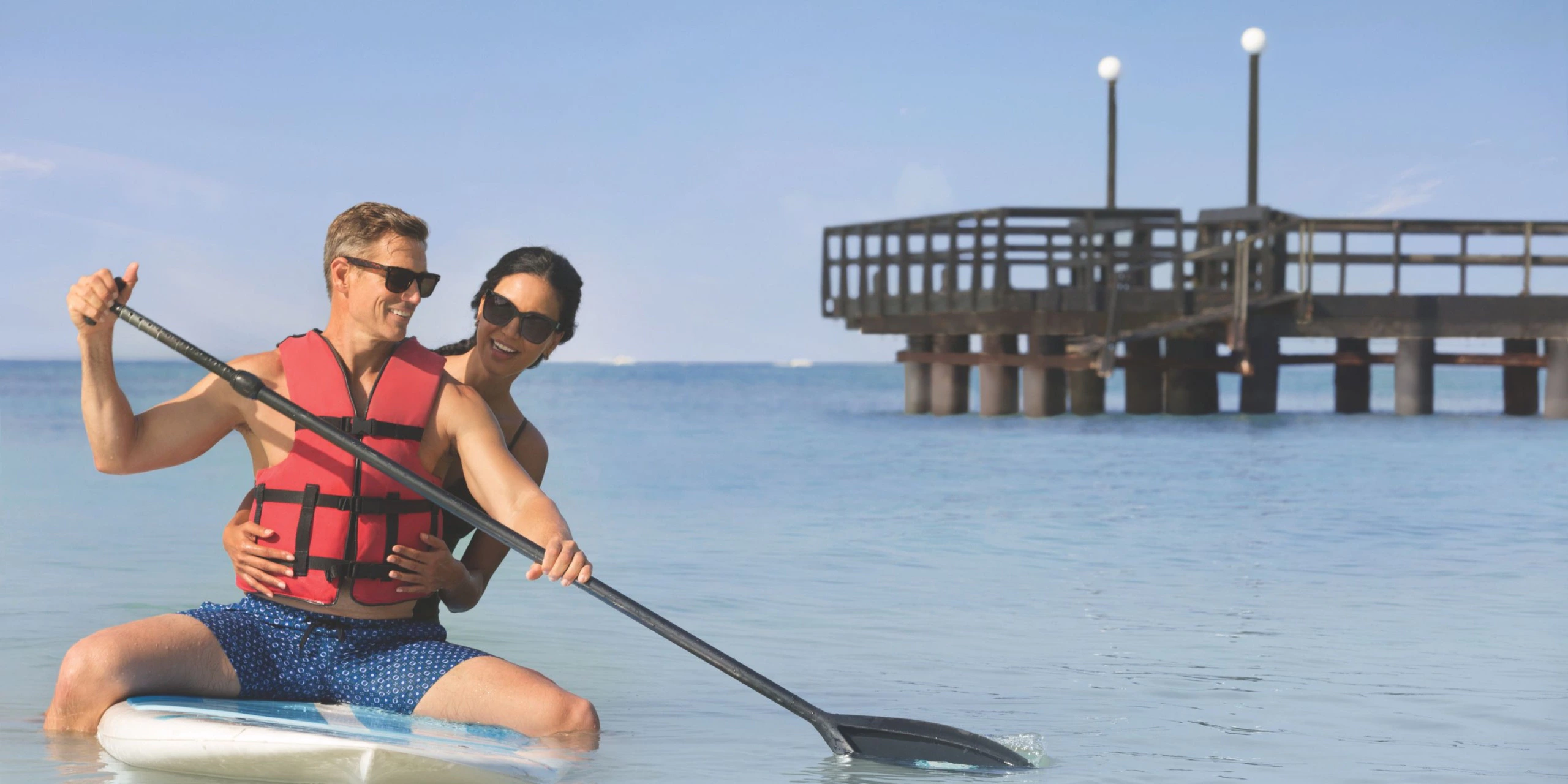 Couple paddleboarding together in calm Caribbean waters at Secrets La Romana Resort & Spa.