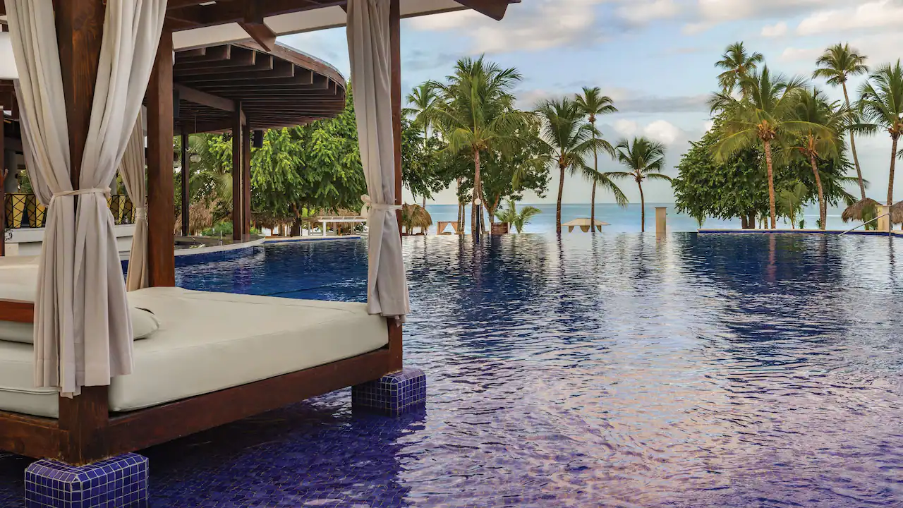 Luxury pergola cabanas beside the infinity pool at Secrets La Romana Resort & Spa in the Dominican Republic.