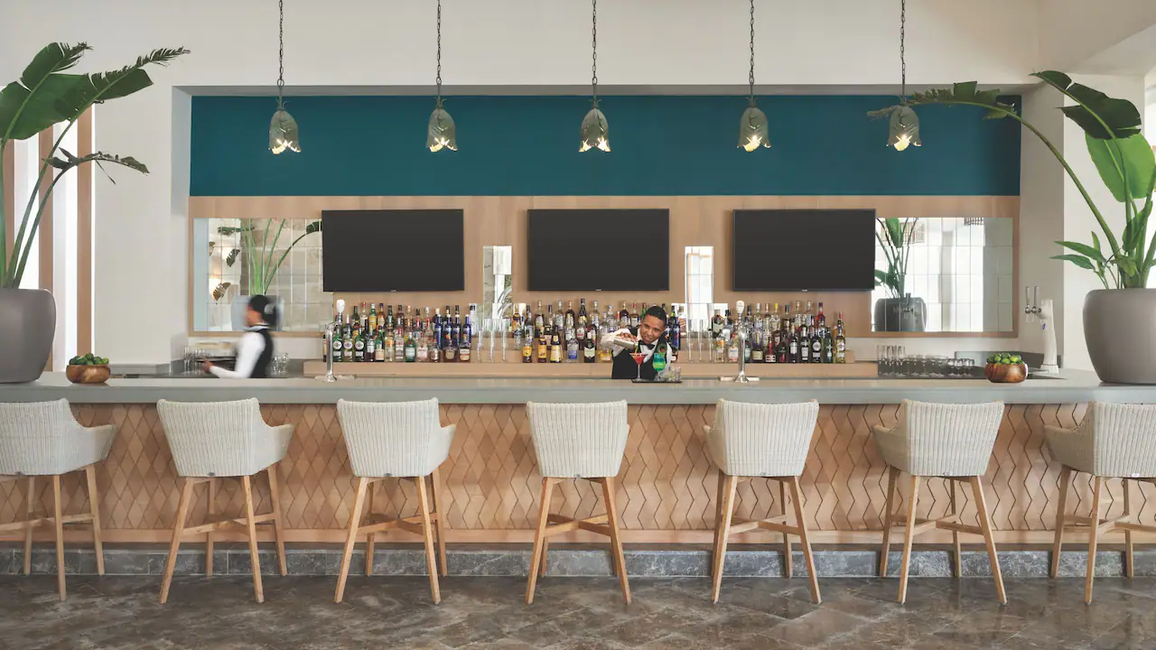 Stylish lobby bar with premium cocktails and modern seating at Secrets La Romana Resort & Spa.