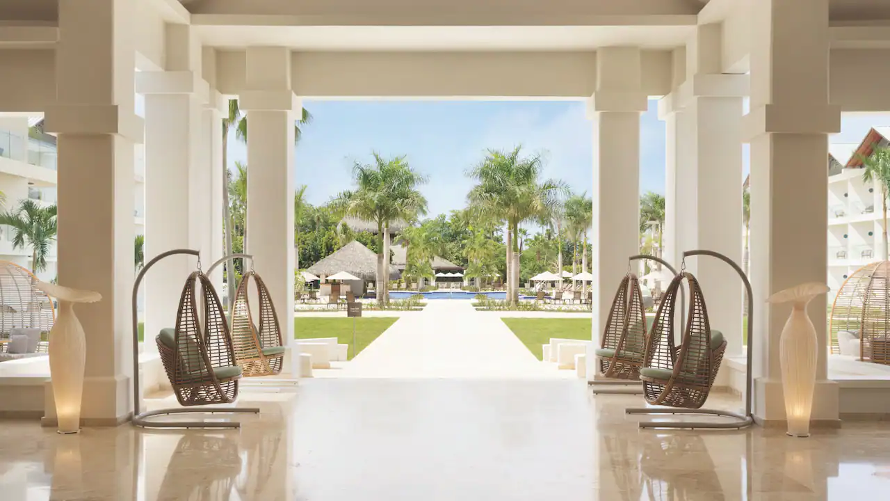 Elegant open-air lobby lounge with hanging chairs at Secrets La Romana Resort & Spa in the Dominican Republic.