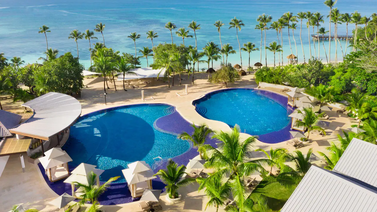 Aerial view of the main resort pool and palm-lined beach at Secrets La Romana Resort & Spa.