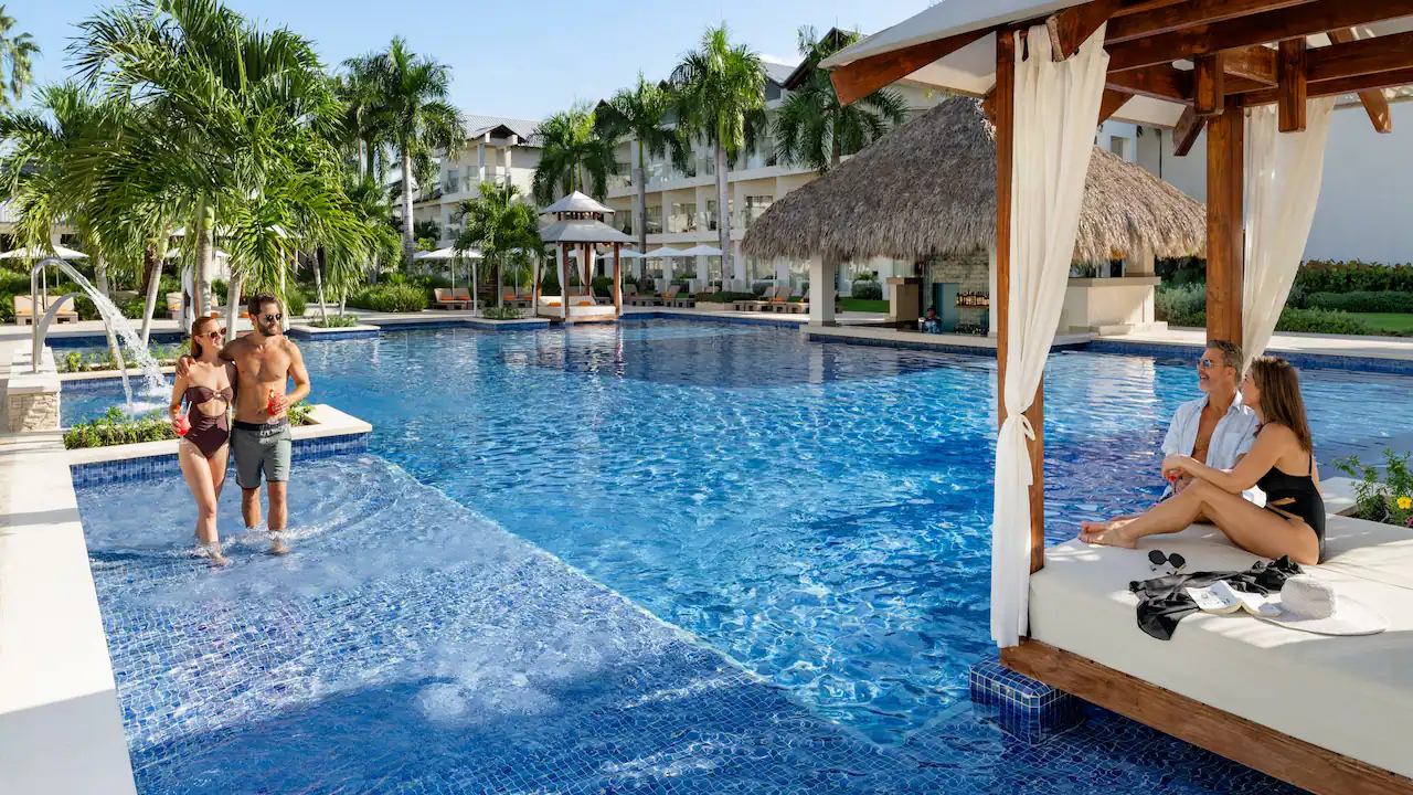 Couples relaxing by the premium pool cabanas at Secrets La Romana Resort & Spa.