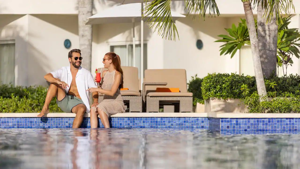 Couple enjoying drinks by the pool at Secrets La Romana Resort & Spa in the Dominican Republic.