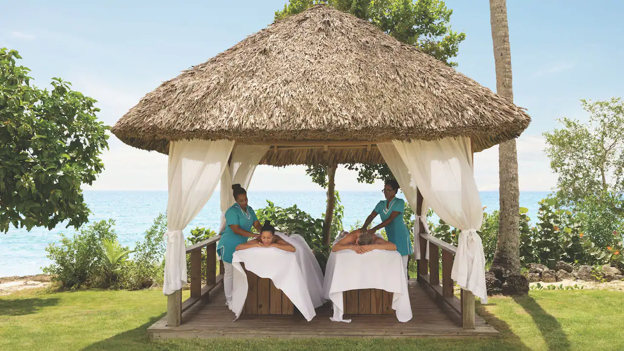 Guests enjoying beachfront massages under tropical spa palapas at Secrets La Romana Resort & Spa.