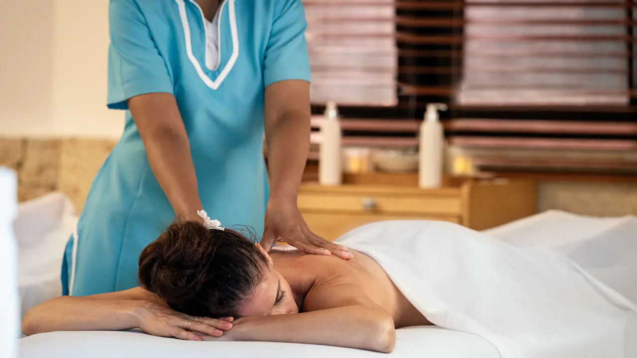 Guest receiving a relaxing massage treatment at the spa inside Secrets La Romana Resort & Spa.