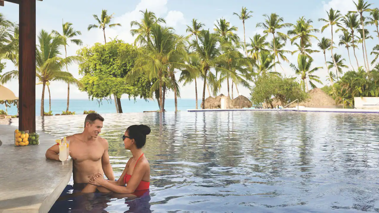 Couple enjoying cocktails at the swim-up bar at Secrets La Romana Resort & Spa.